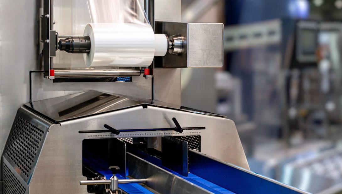 Industrial film handling machinery with roll feed and conveyor system in production line