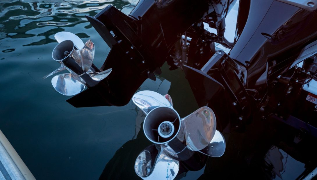 Twin stainless steel boat propellers on marine outboard engines in water