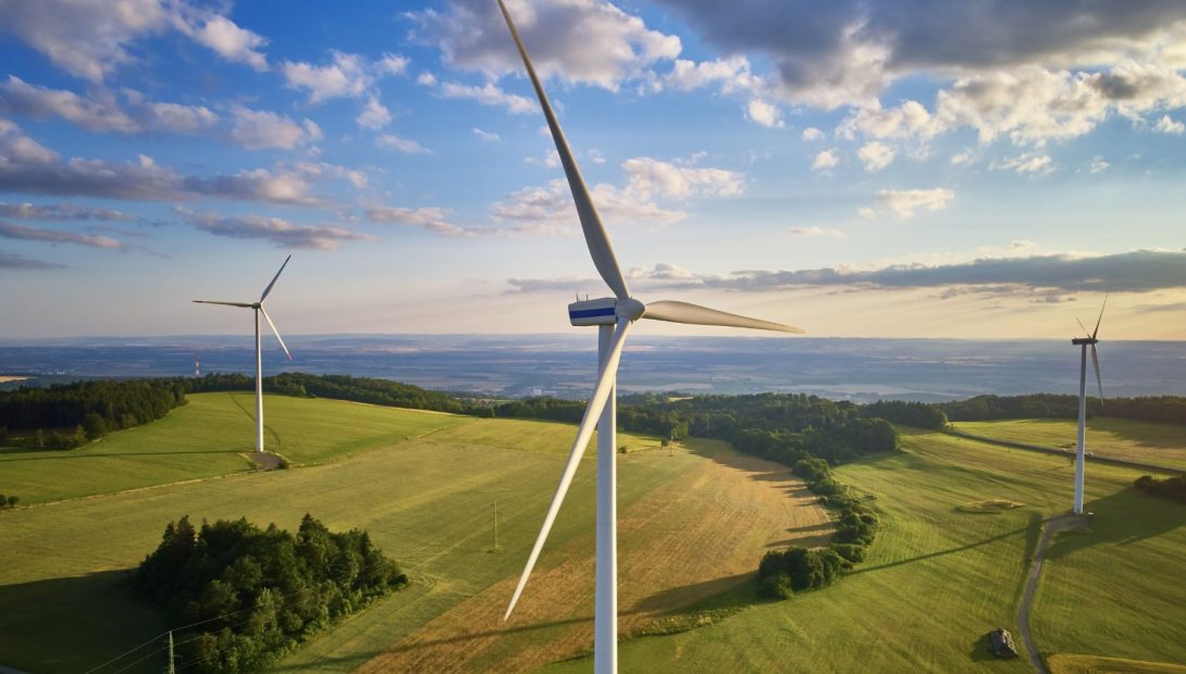 Wind turbines generating renewable energy over rolling countryside farmland